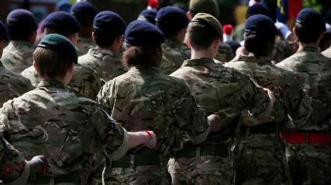 Several women soldiers wearing khaki uniforms and blue berets on parade