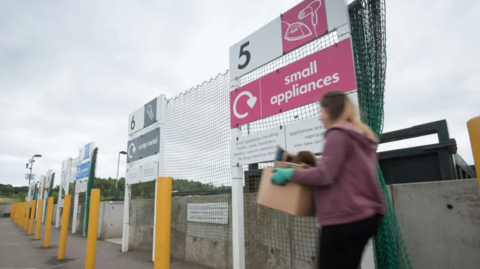 A woman taking rubbish to a container at an unidentified Oxfordshire tip.