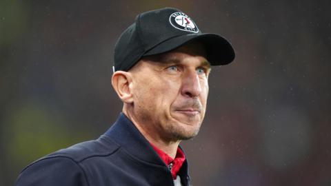 Gerhard Struber wearing a Bristol City cap standing on the pitch following a atch 