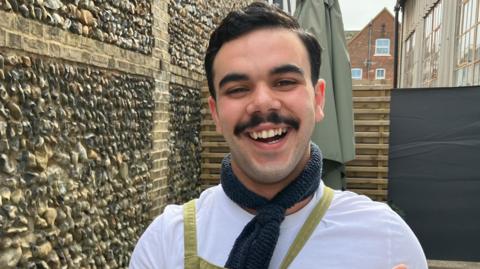 Diego - smiling, wearing a black scarf and white T-shirt