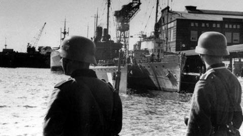 Two soldiers overlooking a docked ship.