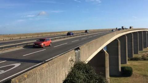 A bridge with a red car driving over it 