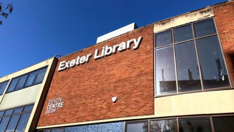 The frontage of Exeter Library with a white sign on red brick.
