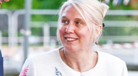 A woman with pale blonde hair and a white top looking upwards slightly