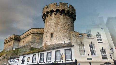 The composite image shows the Admiral McBride pub painted black and white with a tower superimposed on the back of it. Showing were the original Barbican Fort tower used to be centuries ago.