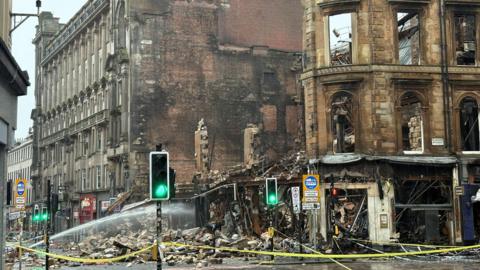 A building devastated by fire, with rubble lying on the street 