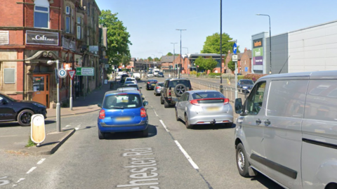 A library shot from Google Streetview showing traffic backed-up on Manchester Road in Altrincham.