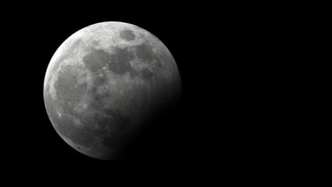 A partially eclipsed full moon against a starkly black night sky