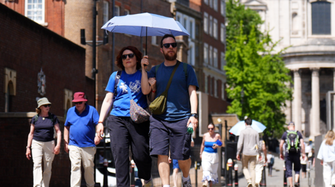 A person uses an umbrella to shelter from the hot weather near St Paul's Cathedral