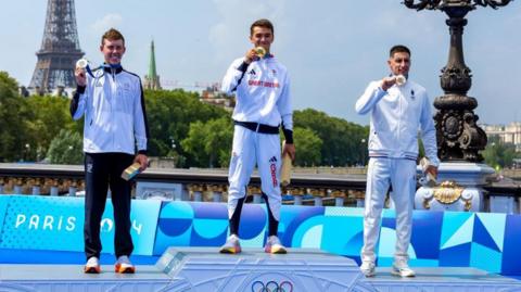 Gold medallist Alex Yee of Great Britain (centre), Silver medallist Hayden Wilde of New Zealand (left) and Bronze medallist Leo Bergere of France (right)