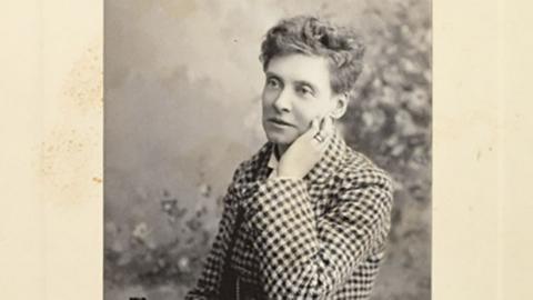 Black and white photograph of Emily Langton Massingberd she has short hair and is wearing a black and white checked jacket