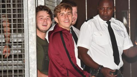 Albert Bowers (left) and Jessie Cole (centre), smiling, appearing to laugh or mock the assembled media, as they leave Reading Magistrates Court following an appearance in relation to the death of PC Andrew Harper.