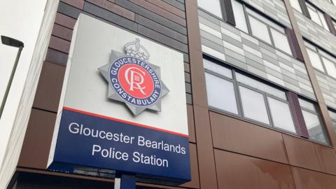 A outside Gloucester Bearlands station featuring the Gloucestershire constabulary logo which is circular and a mixture of red and blue with white lettering