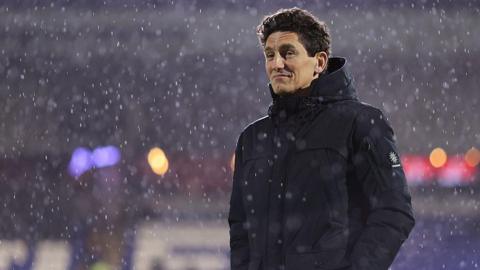 Keith Andrews, wearing a dark winter coat, stands in the pouring rain looking pensive
