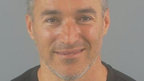 A police custody photo shows Peter Black smiling. He has brown eyes and grey hair and whiskers.