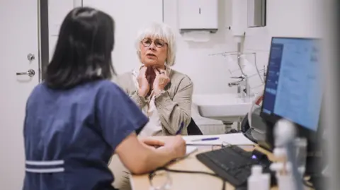 Woman in GP surgery holding side of her neck