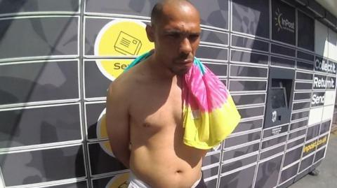 A topless man with his hands behind his back