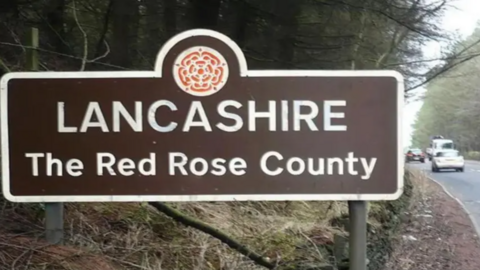 A Lancashire, The Red Rose County, sign by the side of a road as cars drive past