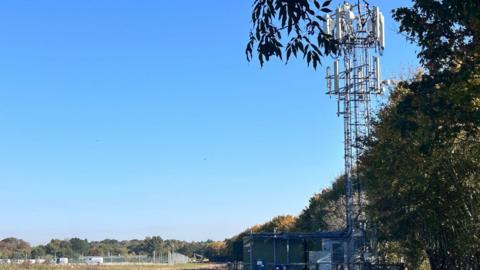 A tall phone mast standing in a field.