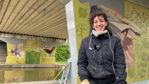 Emma Garness poses beside murals at Beverley Beck