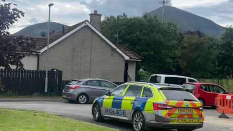 Police car outside house with Mourne Mountains in the background