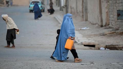 An Afghan burqa-clad woman walks along a street in the 7th district of Afghanistan's Kandahar on August 11, 2026.