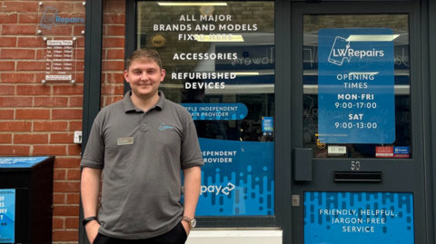 Lewis Watson standing outside shop with blue notices on the doors and windows