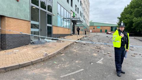 A police officer stands in front of tape blocking off access to the Holiday Inn Express Hotel in Tamworth which was attacked by a mob on August 4th. Behind the tape bricks are strewn all across the road in front of the hotel's entrance which people used to smash windows.    