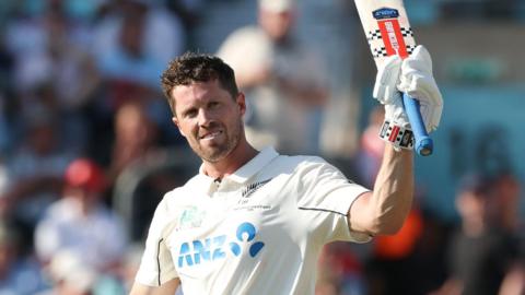 New Zealand batter Henry Nicholls raises his bat after hitting a century