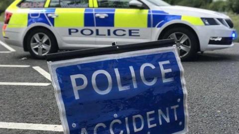 A sign saying "police accident" and a police car in the background