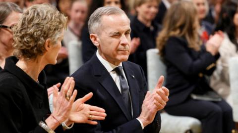 Mark Carney winks as he applauds during a ceremony to swear him in as Canada's prime minister