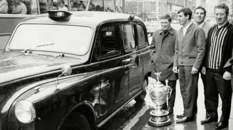 Keith Hepworth (left) stood next to a black cab with Castleford team-mates in London after the 1969 Challenge Cup final win