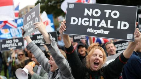 Protesters hold signs during a 'No to Digital ID' demonstration against the planned introduction of a government-issued digital ID for all British adults, near to the Labour Party Conference in Liverpool, Britain, September 28, 2025.