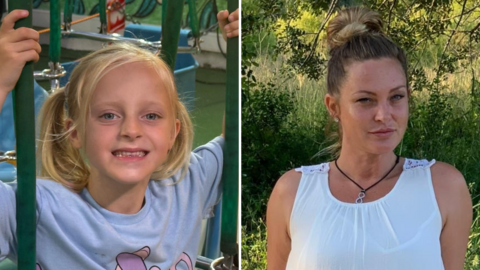 Mary Michelle Devine right in a white dress in a green outdoor area and Theia left in a play area smiling at the camera. She is a blond haired girl wearing a purple t-shirt with a cartoon character on.