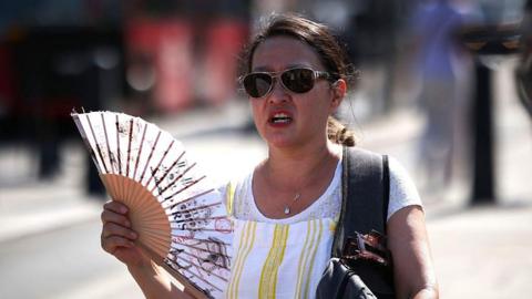A woman uses a fan to cool down on June 26, 2026 in London, England