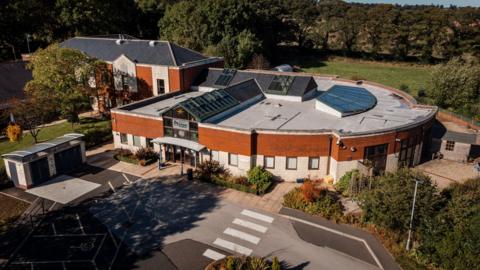 An aerial view of Ashgate Hospice, a semi circular building with the bottom half in white brick and the top half in red brick