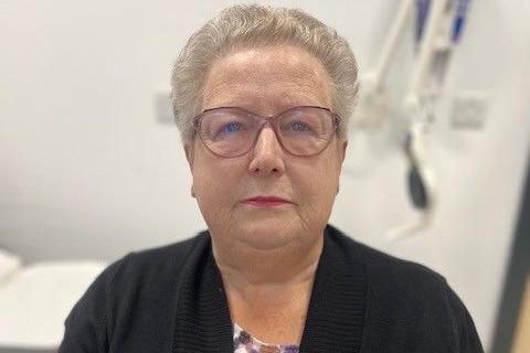Margaret Junner, an older woman with short grey hair and glasses, wearing a dark coloured cardigan, looks at the camera.