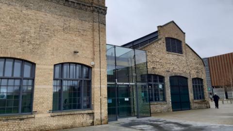 Sand Martin House is a large brick building with large windows and a glass atrium at the entrance