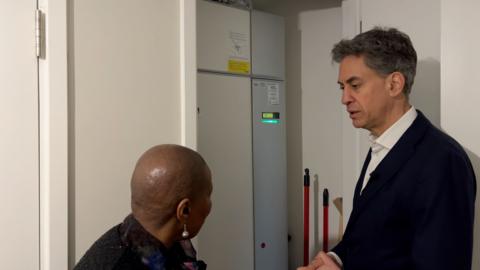 Ed Miliband looks at the heat pump installed in a recently built flat in Reading with the tennant living there.