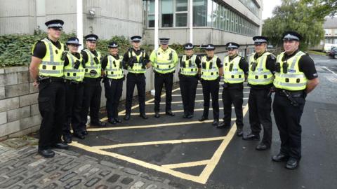 A group of police officers in high visibility tops and black uniforms stands outside Scottish Borders Council's headquarters