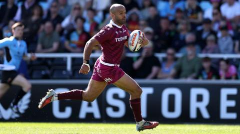 Tom O'Flaherty in full stride with the ball under his left arm for Sale in the sunshine against Harlequins