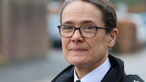 A head shot of Rachel Kearton, who has dark greying hair pulled back from her face and is wearing dark rimmed glasses. She is also wearing a navy police jacket over a white shirt and tie. 