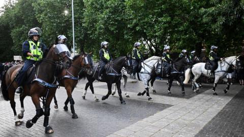 A line of mounted police officers in riot gear seen moving through central Bristol. 