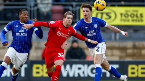 Llun o 2 chwaraewr Caerdydd ac un chwaraewr Leyton Orient a'r bel yn yr awyr yn ystod y gem. 