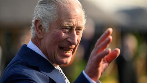 King Charles smiles and waves 