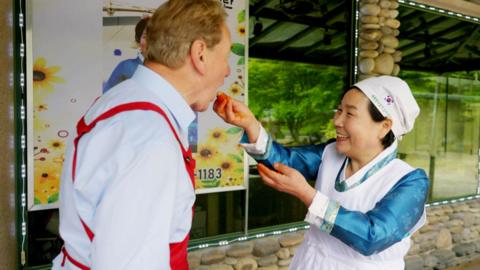 Michael Portillo is being hand-fed kimchi by a prize-winning kimchi maker.