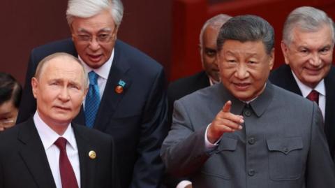 Russian President Vladimir Putin and Chinese President Xi Jinping stand next to one another