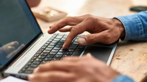 A man's hands typing on a keyboard