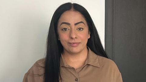 Arooj Shah has long black hair and is wearing khaki shirt