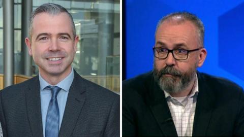 Pól Deeds has grey hair and is smiling at the camera and Lee Reynolds has thinning hair and a grey beard and thick dark glasses. They are both wearing shirts and blazers